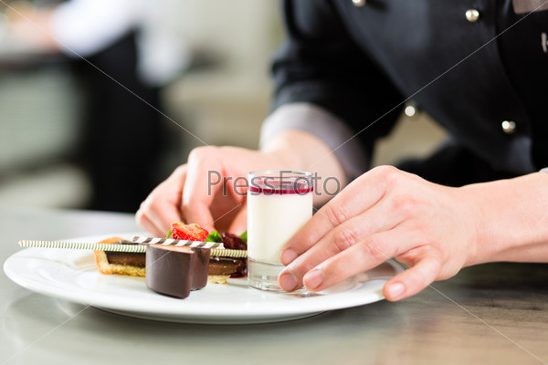 Cook, the pastry chef, in hotel or restaurant kitchen cooking, he is finishing a sweet dessert