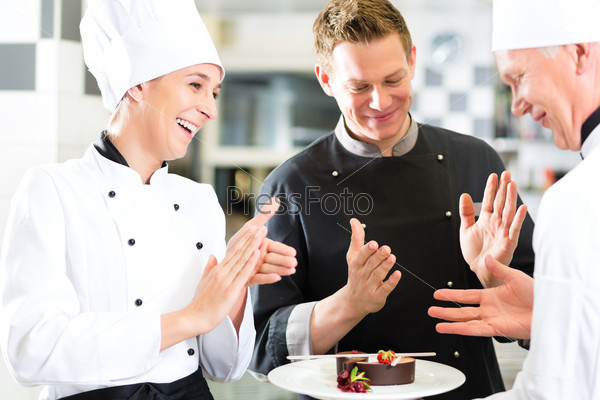 Chef team in restaurant kitchen with dessert, the colleagues applauding because the dish works great