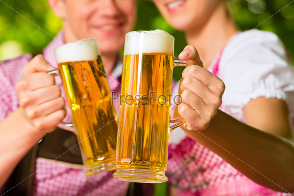 Happy Couple sitting in Beer garden in summer and enjoy a glass of beer and the sun