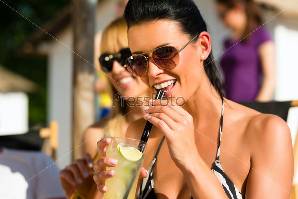 People at beach drinking having a party, woman or girl in front drinking cocktail