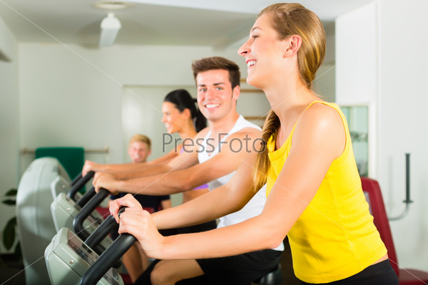 Group of men and women train on machine in a fitness club or gym , stock photo