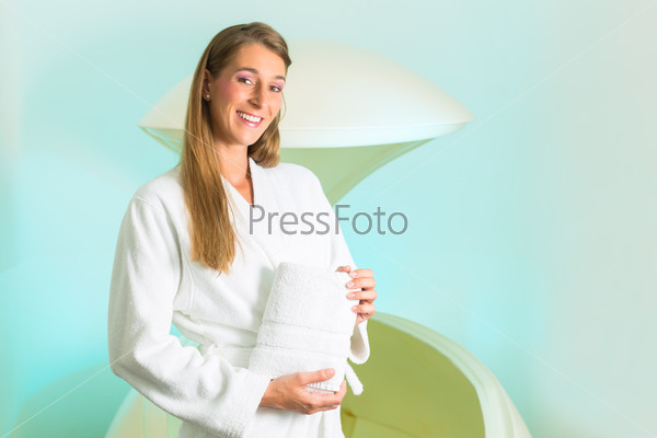 Wellness - young woman floating in Spa or swimming pool, next to her the floating Tank