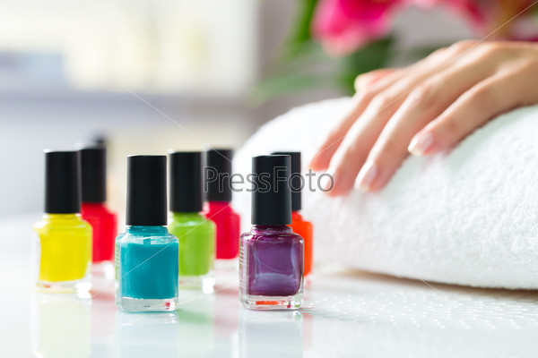 Woman in a nail salon receiving a manicure, there are colorful nail polish