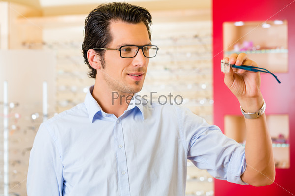 Young man at optician with glasses, he might be customer or salesperson