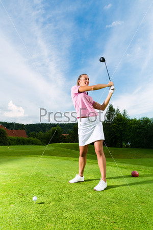 Young female golf player on course doing golf swing, she presumably does exercise