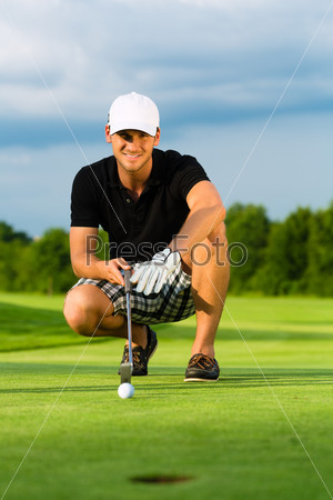 Young golf player on course putting, he aiming for his put shot