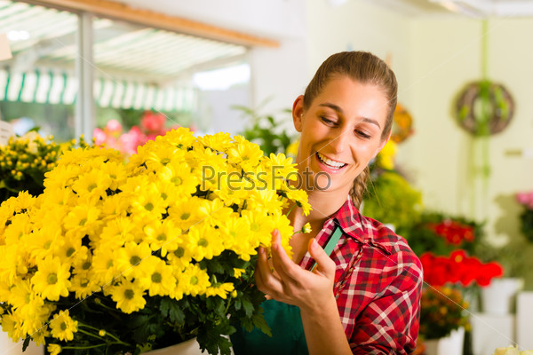Female florist in flower shop or nursery presenting flowers