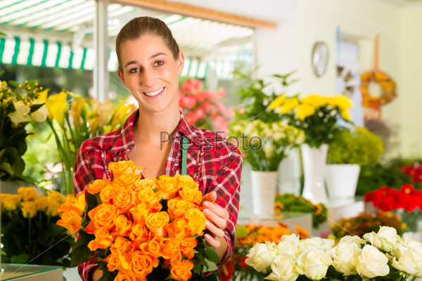 Female florist in flower shop or nursery presenting roses