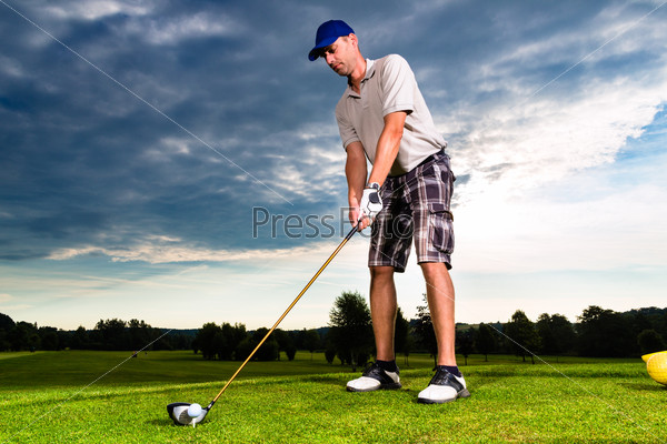 Young golf player on course doing golf swing, he presumably does exercise, stock photo