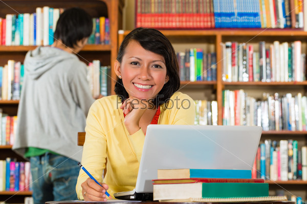 Девушка в библиотеке с ноутбуком