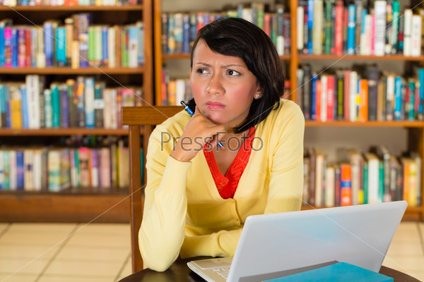 Student - Young woman in library with laptop learning, she is concentrated