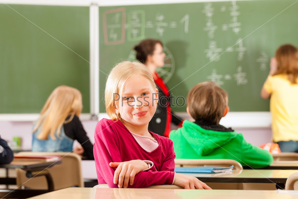 Education - Young female teacher with pupil in his form of the elementary or primary school teaching