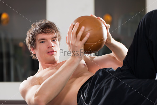 Muscular man exercising by doing push ups with only one arm in a gym