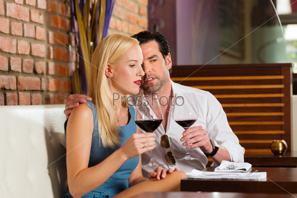 Attractive young couple drinking red wine in restaurant or bar, it might be the first date