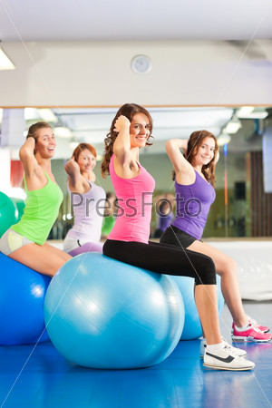 Fitness - Young women doing sports training or workout with gymnastic ball in a gym, stock photo