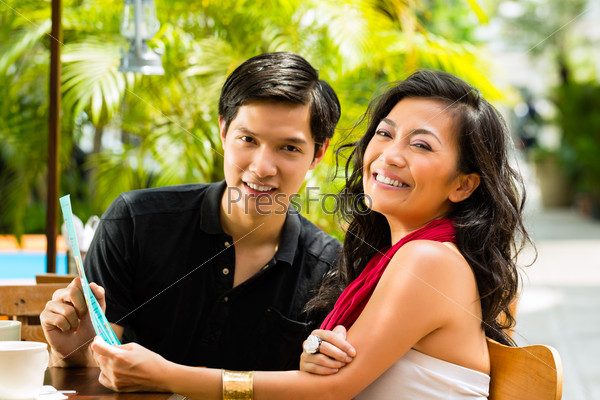 Asian man and woman in restaurant are selecting the food and are hungry, stock photo