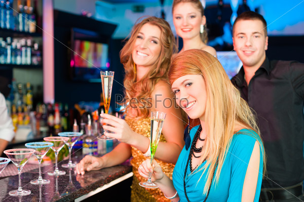 Young people in club or bar drinking champagne and having fun; all are looking into the camera, stock photo