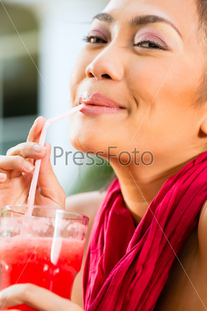Asian woman in restaurant is drinking nonalcoholic fruit juice