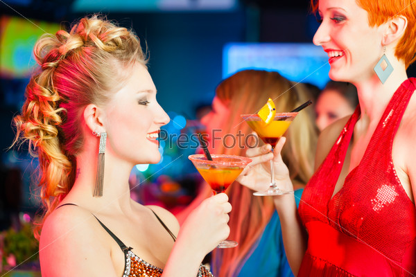 Young women in club or bar drinking cocktails and having fun, stock photo