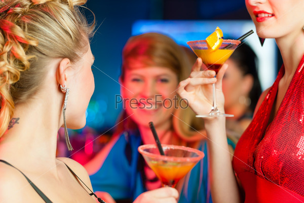 Веселые молодые женщины в баре пьют коктейли