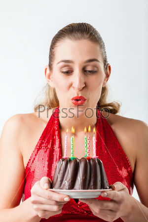 Woman celebrating birthday with cake blowing candles out