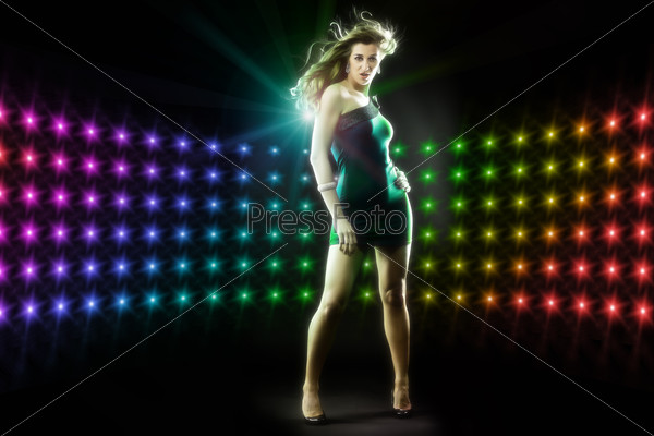 Beautiful young girl or woman dancing in a club disco to the music, lots of lights visible