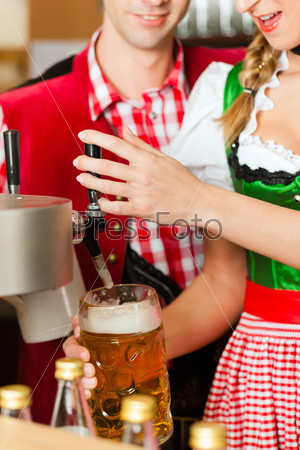 Young woman drawing beer in restaurant or pub, she is the innkeeper