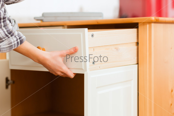 Young woman is assembling a cupboard because she is moving in or out - only hand to be seen