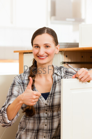 Young woman is assembling a cupboard because she is moving in or out - thumps up