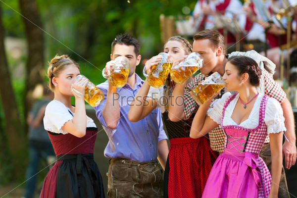 In Beer garden in Bavaria, Germany - friends in Tracht, Dirndl and Lederhosen and Dirndl standing in front of band