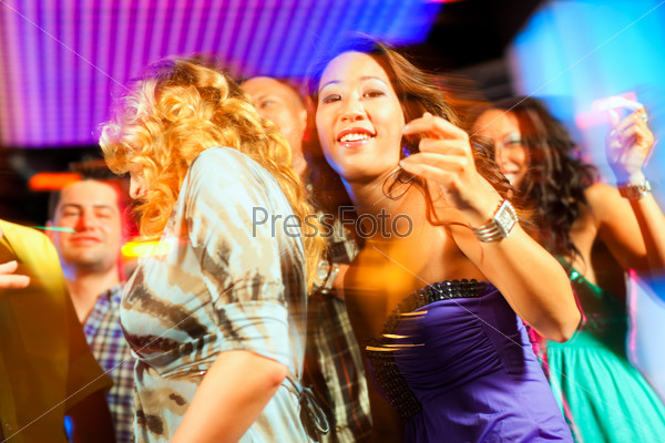 Group of party people - men and women - dancing in a disco club to the music, stock photo