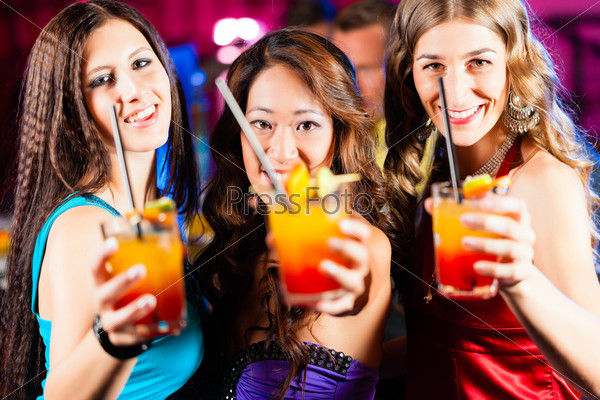 Group of party people - three female girl friends - with cocktails in a bar or club having fun