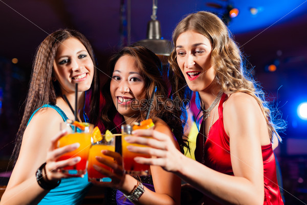 Group of party people - three female girl friends - with cocktails in a bar or club having fun, stock photo