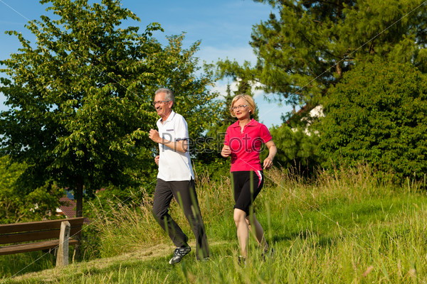 Nordic Walking - Happy mature or senior couple doing sports in summer outdoors, stock photo