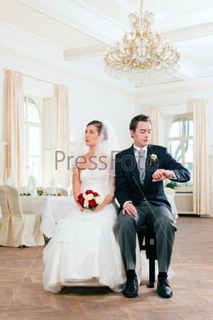 Bridal couple waiting for ceremony - he is already checking the time