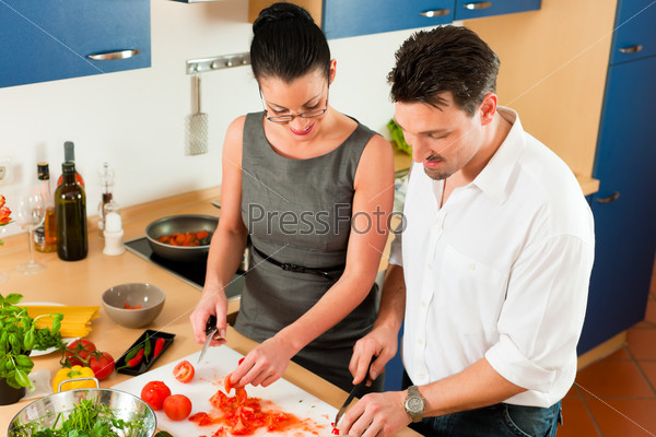 Man and woman in the kitchen - they preparing the vegetables and salad for dinner or lunch