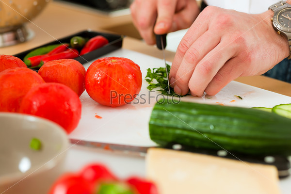 Man in the kitchen - only hands to be seen - is preparing the vegetables for dinner or lunch