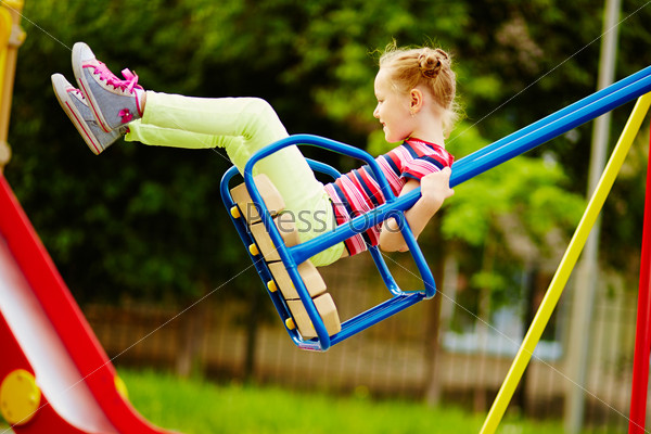Happy little girl swinging on playground area