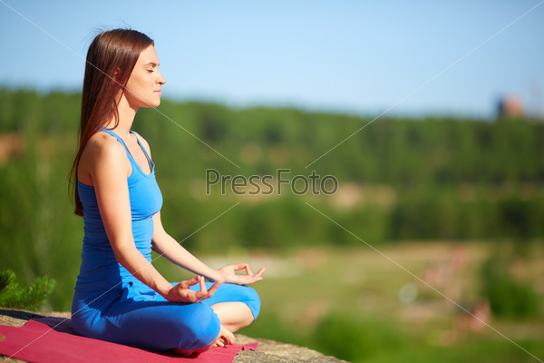 Profile of meditating woman relaxing in pose of lotus outdoors