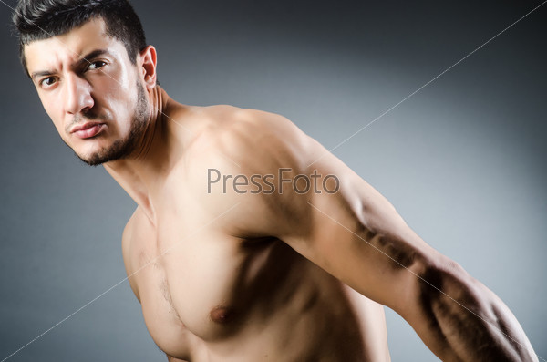 Muscular man posing in dark studio, stock photo