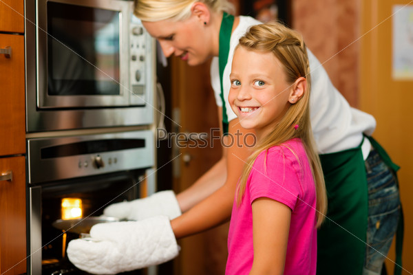 Mother and daughter cooking Ã¢Â?Â? they are putting roast in the oven