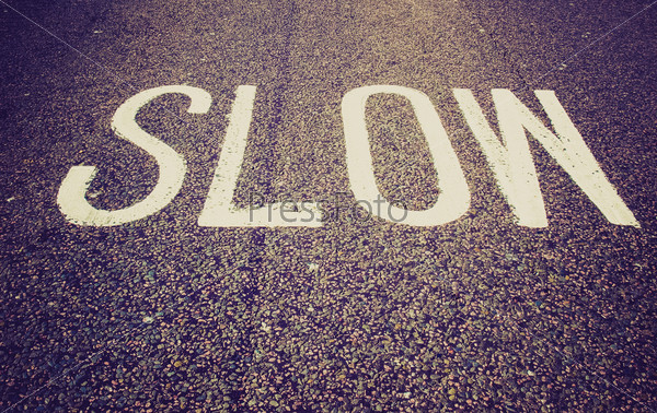 Vintage retro looking Slow warning sign painted on a street