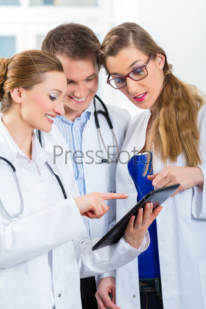 Team of young doctors in clinic with tablet computer