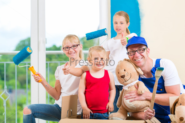 Family moving house with boxes full of stuff, they are painting the walls of their new home, stock photo