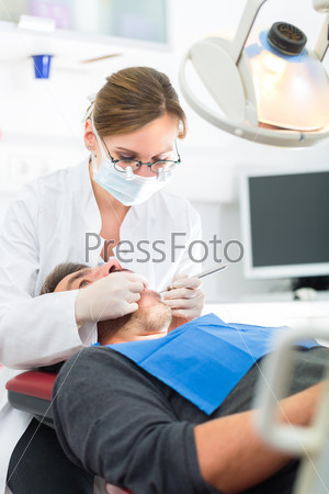 Male patient with female dentist in a dental treatment, wearing masks and gloves