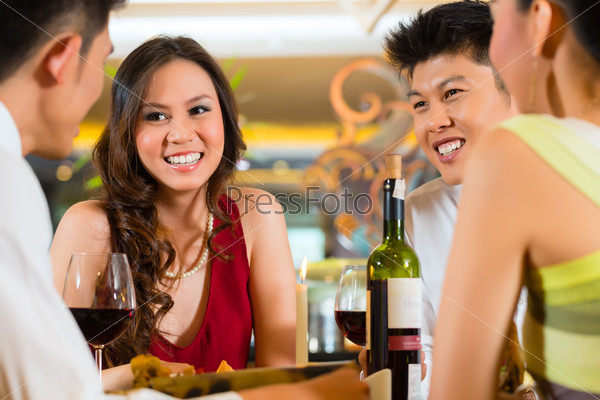 Four Asian Chinese business people having dinner in elegant club restaurant or hotel, stock photo