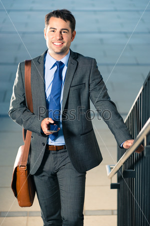 Handsome businessman or manager using phone and going to business appointment or home