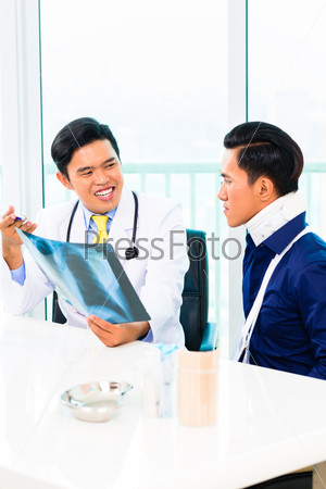 Asian doctor showing patient with toby collar his radiograph in medical practice or surgery