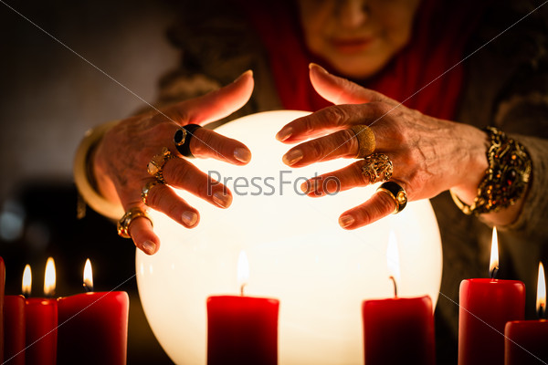 Female Fortuneteller or esoteric Oracle, sees in the future by looking into their crystal ball during a Seance to interpret them and to answer questions