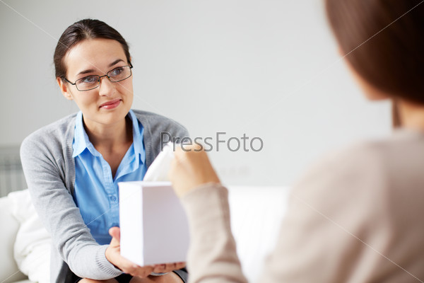 Careful psychiatrist giving box with paper tissues to her patient, stock photo